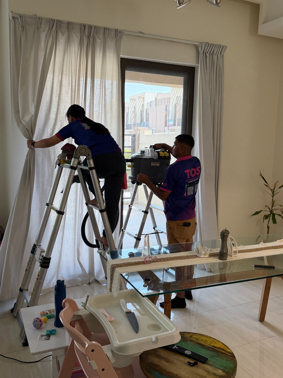 TopOne Services technicians steam cleaning curtains on site in a Dubai apartment